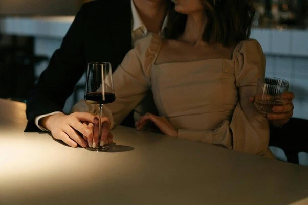 Muž drží ruku ženy při společném pití v restauraci.