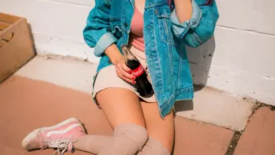 Dívka sedí s lahví Coca-Coly v ruce.