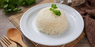Hromada uvařené bílé rýže na talíři s petrželkou.