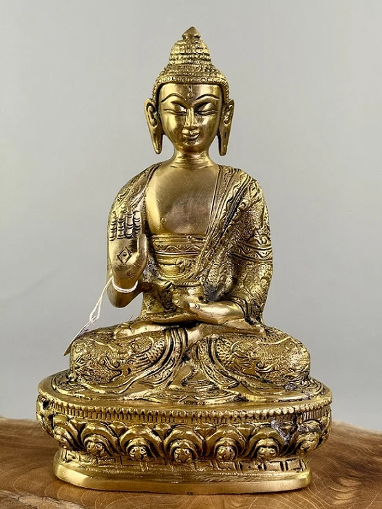 Zlatá socha Buddhy se zvednutou rukou v meditaci