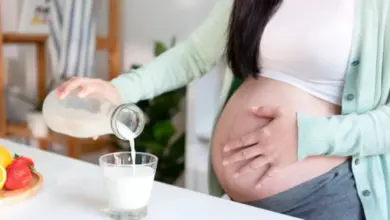 Těhotná žena nalévá mléko do skla jako zdroj vápníku.