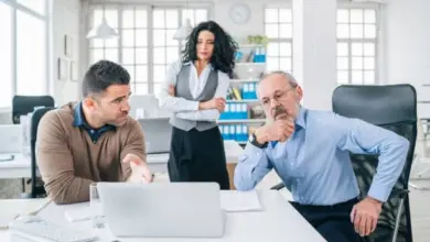Tři profesionálové diskutují v kanceláři u počítače.