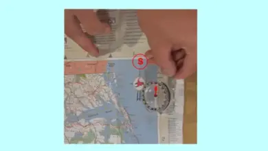 Kompas na mapě s rukama určující světové strany