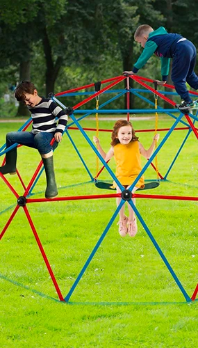 Děti hrají na barevném venkovním hracím zařízení v parc.
