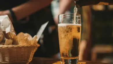 Pivo se nalévá do sklenice na dřevěném stole.