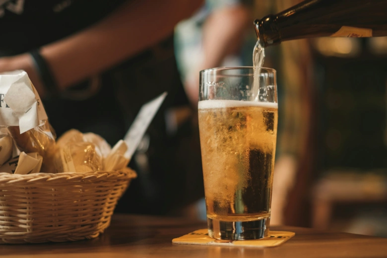 Pivo se nalévá do sklenice na dřevěném stole.