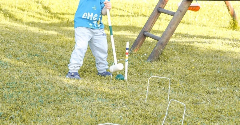 Dětská hra kriket na trávníku venku s hůlkou.