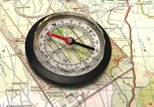 Kompas položený na turistické mapě pro orientaci v terénu.