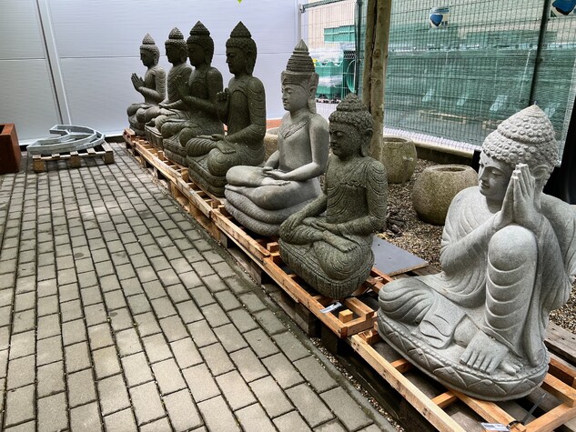 Řada kamenných soch Buddhy v meditaci s různými gesty rukou.