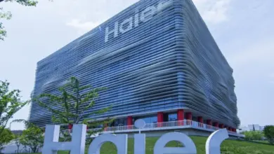 Modern budova společnosti Haier s velkým logem na trávníku.