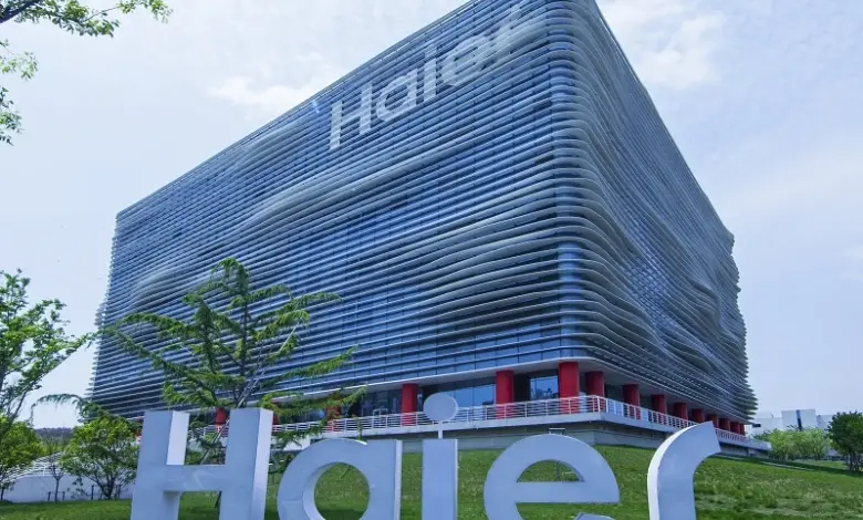 Modern budova společnosti Haier s velkým logem na trávníku.
