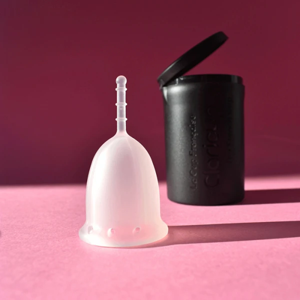 Průsvitný menstruační šál s černým pouzdrem na růžovém pozadí.