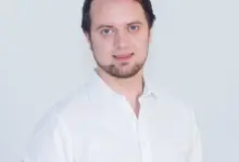 Muž v bílé košili na neutrálním pozadí pro článek o ramenní impingement syndromu.