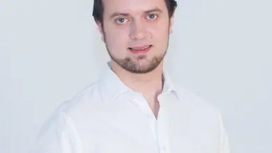 Muž v bílé košili na neutrálním pozadí pro článek o ramenní impingement syndromu.