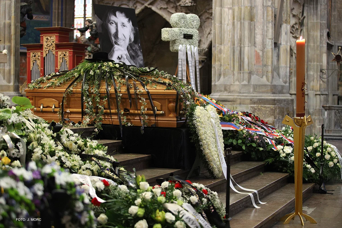 Dřevěný rakev s květinami na mužském pohřebním hrobě v kostele.