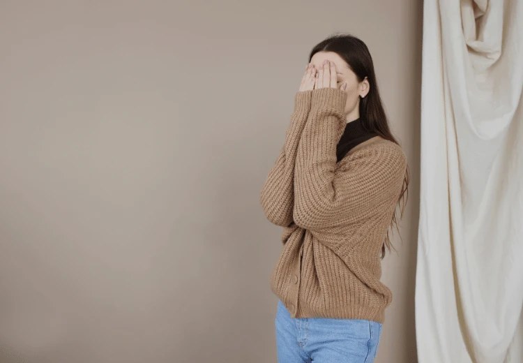 Žena zakrývá obličej rukama jako příznak komplexu méněcennosti.