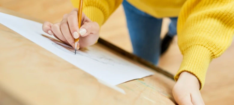 Osoba kreslí tužkou na papíře při práci s různými styly.