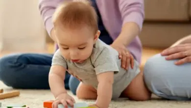Babička s dítětem hraje na podlaze s barevnými kostkami.