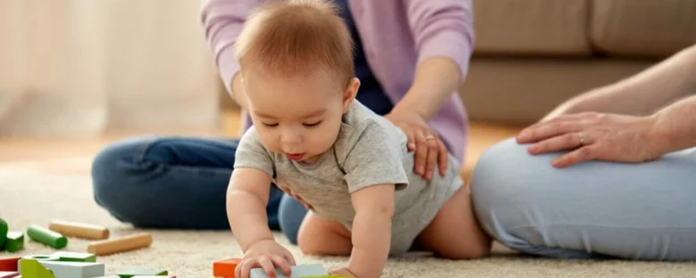 Babička s dítětem hraje na podlaze s barevnými kostkami.