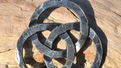 Keltský symbol triquetra jako kovový přívěsek na dřevě.
