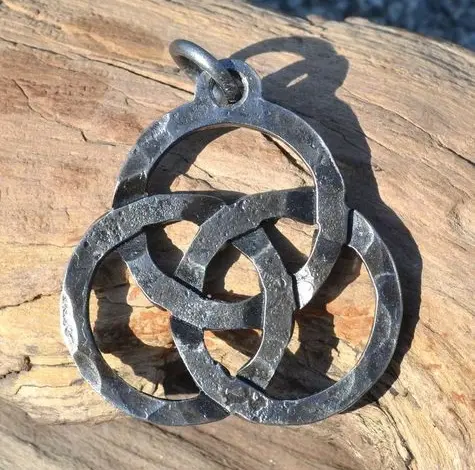 Keltský symbol triquetra jako kovový přívěsek na dřevě.