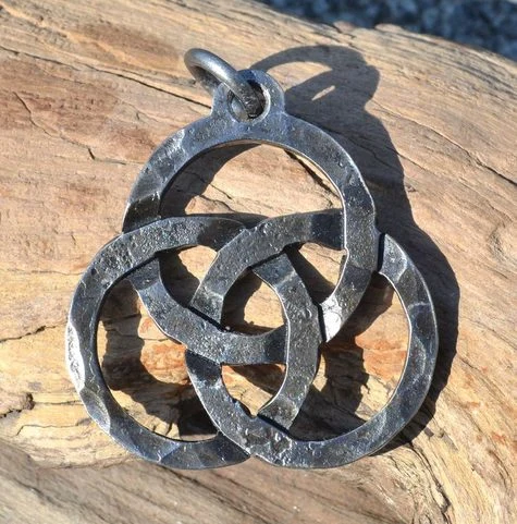 Keltský symbol triquetra jako kovový přívěsek na dřevě.