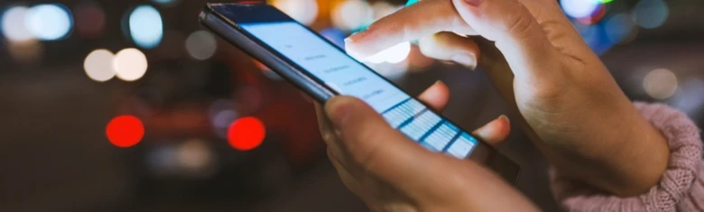 Ruce drží chytrý telefon v noci na ulici.
