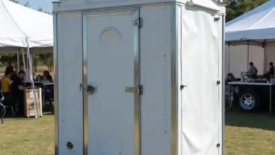 Bílá přenosná toaleta na trávníku během venkovního akce.