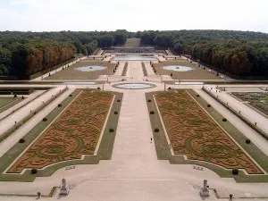 Formální empírový zámecký park s geometrickými květinovými úpravy a fontánami.