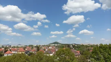 Modrá obloha s bílými mraky nad městem v normálním atmosférickém tlaku.