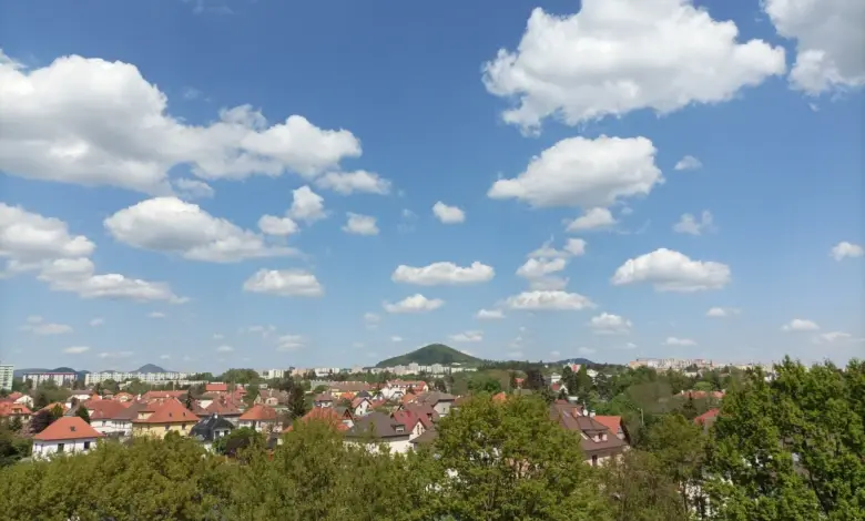Modrá obloha s bílými mraky nad městem v normálním atmosférickém tlaku.