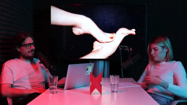 Muž drží ženské nohy na obrazovce během diskuse.