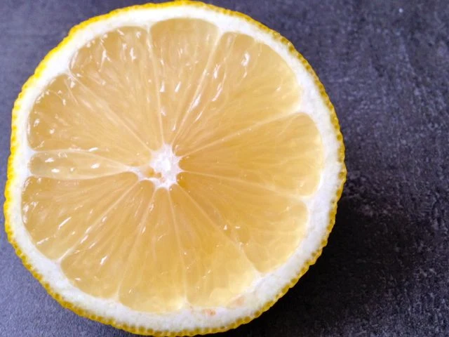 Čerstvý citron nakrájený na polovinu s viditelnými segmenty.