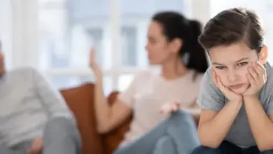 Smutné dítě sedí před hádajícími se rodiči.
