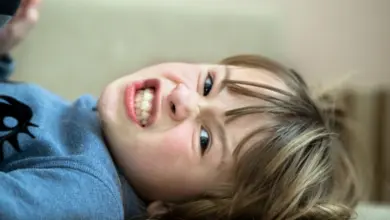 Roztřesené dítě leží na zádech s výrazem hněvu.