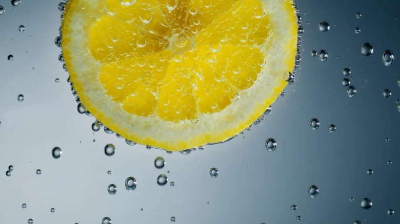 Žlutý citron v bublající vodě, symbol kyselosti.