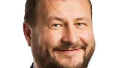 Portrét usměvavého muže v obleku na bílém pozadí.
