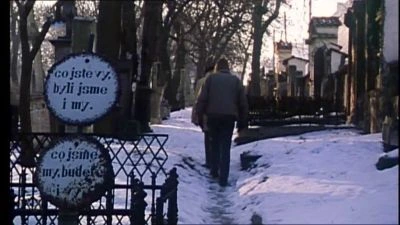 Osoba chodí po sněhu u památných desek s textem.