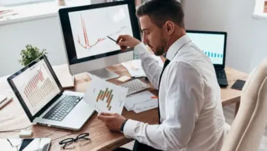 Muž analyzuje grafy produktivity na monitorech v kanceláři.