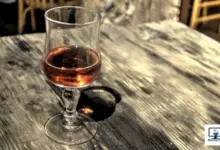 Sklenička s alkoholem na dřevěném stole.