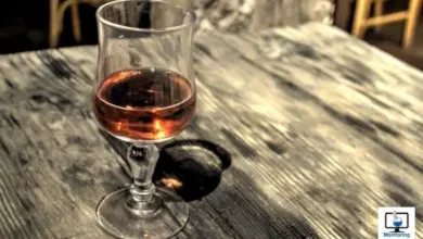 Sklenička s alkoholem na dřevěném stole.