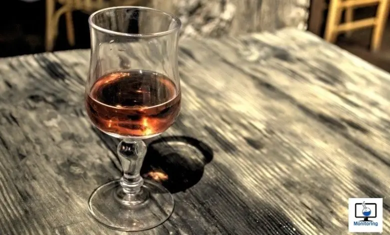 Sklenička s alkoholem na dřevěném stole.