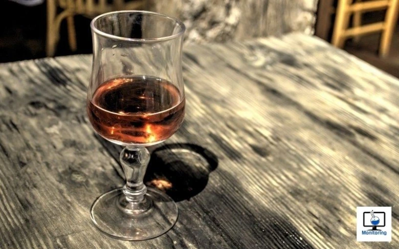Sklenička s alkoholem na dřevěném stole.