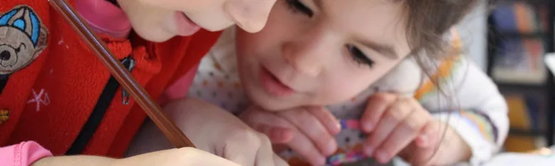 Dětská dívka se učí s pomocí dospělého při studiu.