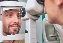 Muž se dívá do optometrického přístroje při vyšetření zraku.
