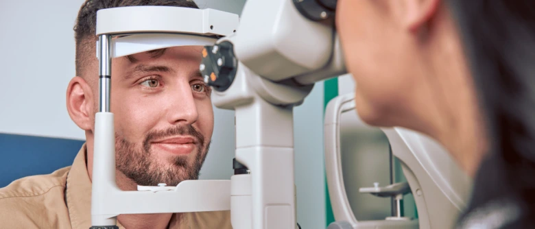 Muž se dívá do optometrického přístroje při vyšetření zraku.