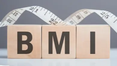 Dřevěné kostky s písmeny BMI vedle měřicí pásky.