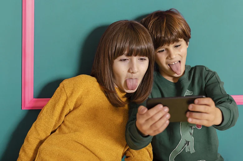 Two kids making faces on phone