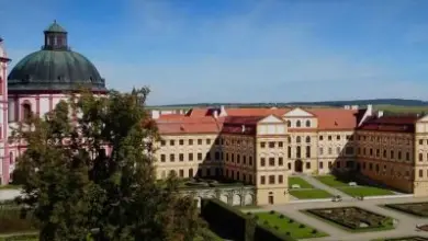 Barokní palác s kupolí a formovanou zahradou.