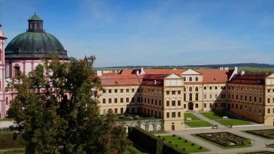 Barokní palác s kupolí a formovanou zahradou.